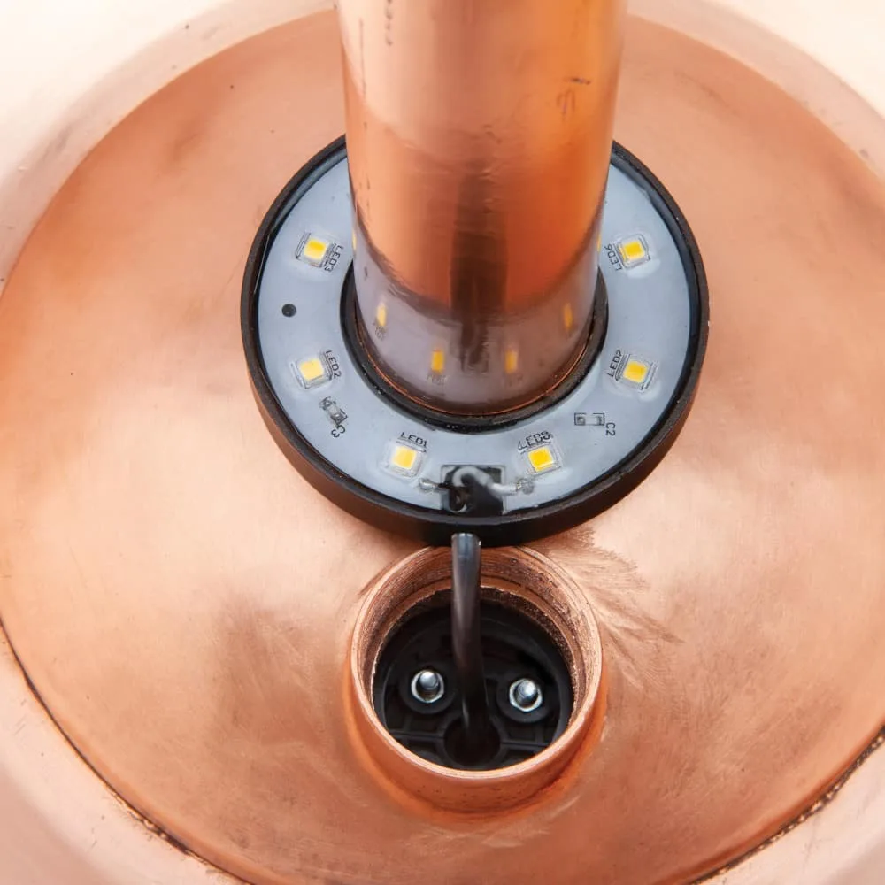 Kobberfontene med LED-ring rundt røret og kabel ført gjennom bunnen