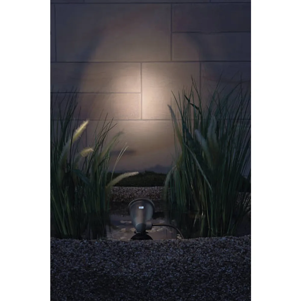 OASE LunAqua Classic LED lyser opp en steinvegg mellom pyntegress om kvelden