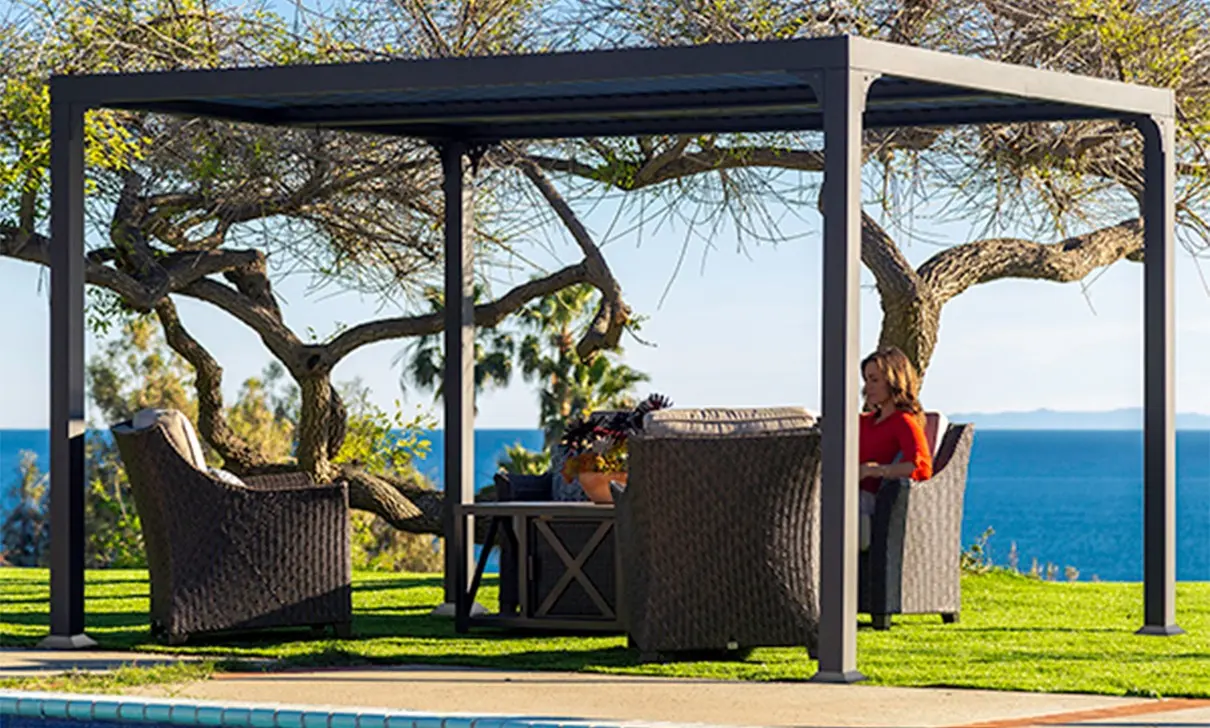 Pergola i grått aluminium med hagemøbler på en plen ved havet, bilde for kategorien pergola