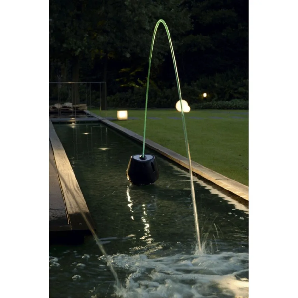 OASE JumpingJet Rainbow Star sender en opplyst vannbue over et smalt basseng om kvelden