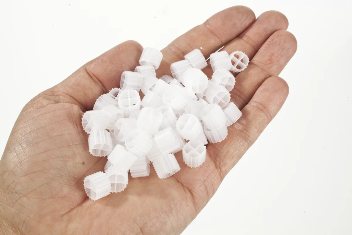 En håndfull K1 Micro filtermedie fra Evolution Aqua, små hvite filterelementer