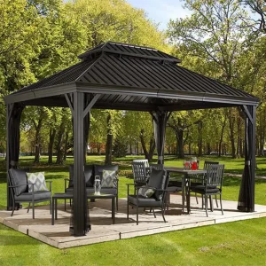 gop Messina Pergola 18 kvm med sort dobbelt ståltak over spisebord og loungemøbler på treplatting i parken