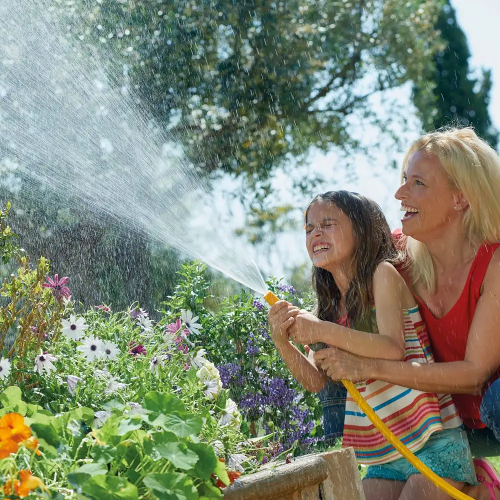 Mor og datter vanner blomsterbedet med Hozelock Superhoze og sprededyse