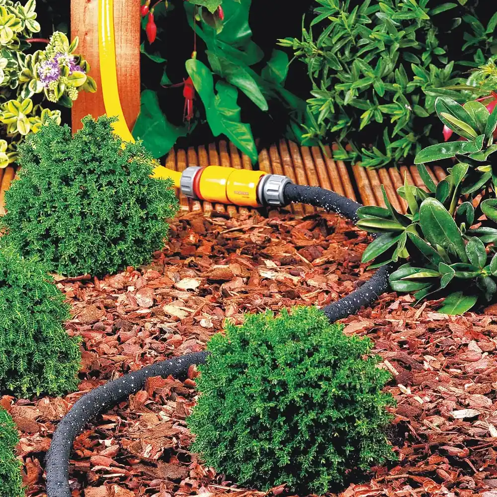 Hozelock svetteslange lagt i blomsterbed med bark, koblet til hageslangen