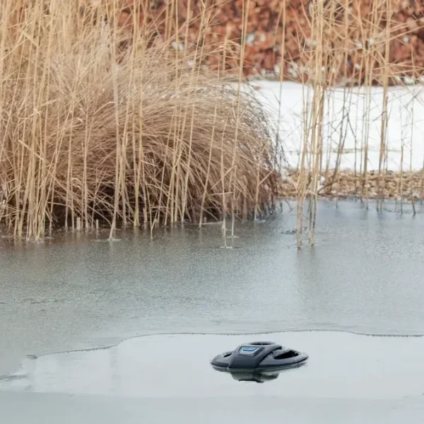 OASE IceFree 4 Seasons holder et hull åpent i isen på en hagedam med siv og snø