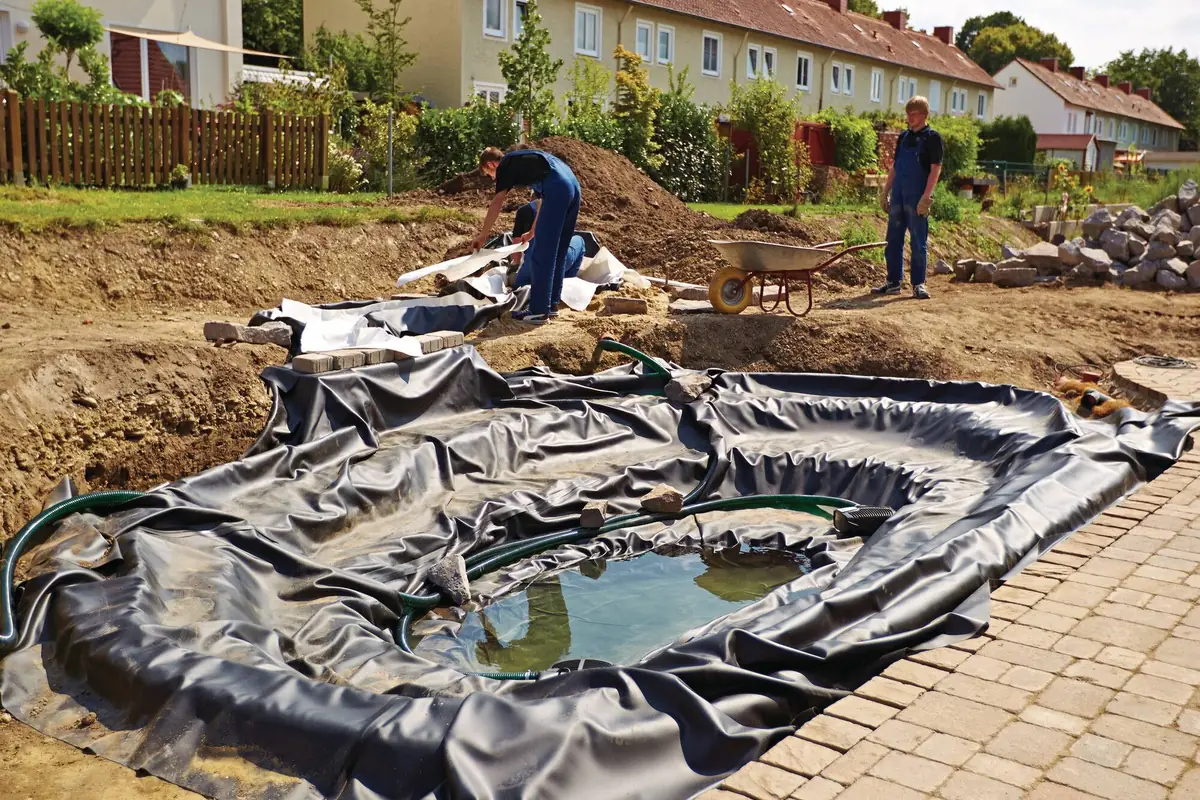 Damfolien ligger på plass og hagedammen fylles med vann fra slange