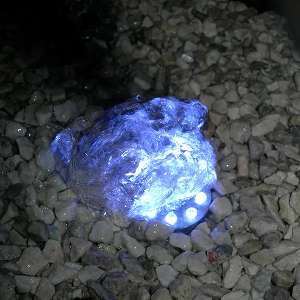 Blått lys fra LED-ring med seks dioder i vannet som renner over en stein i grus
