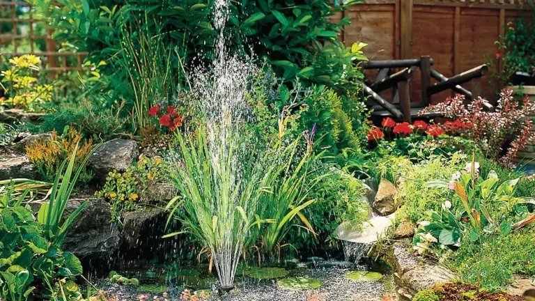 Fontene midt i en liten hagedam med stein, sumpplanter og blomster rundt