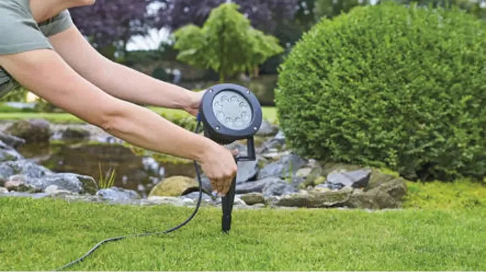 OASE LunAqua Power LED XL stikkes ned i plenen ved dammen med jordspyd