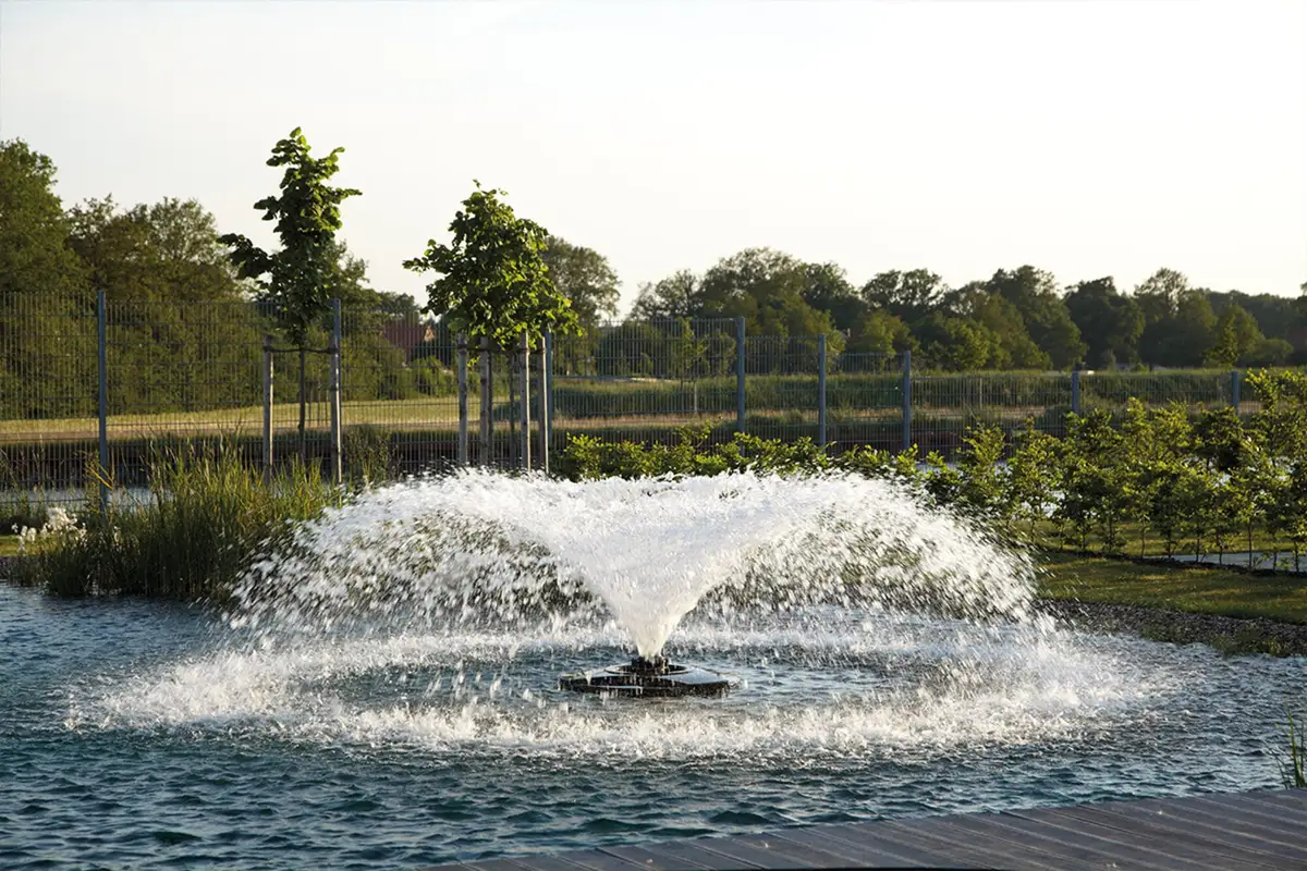 OASE AirFlo lufter med bred vannklokke i en stor parkdam om sommeren
