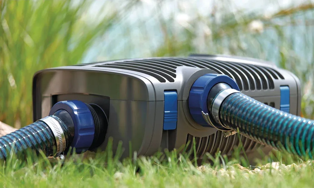 OASE AquaMax Eco Premium 12 V filterpumpe med to slanger tilkoblet i gresset ved dammen