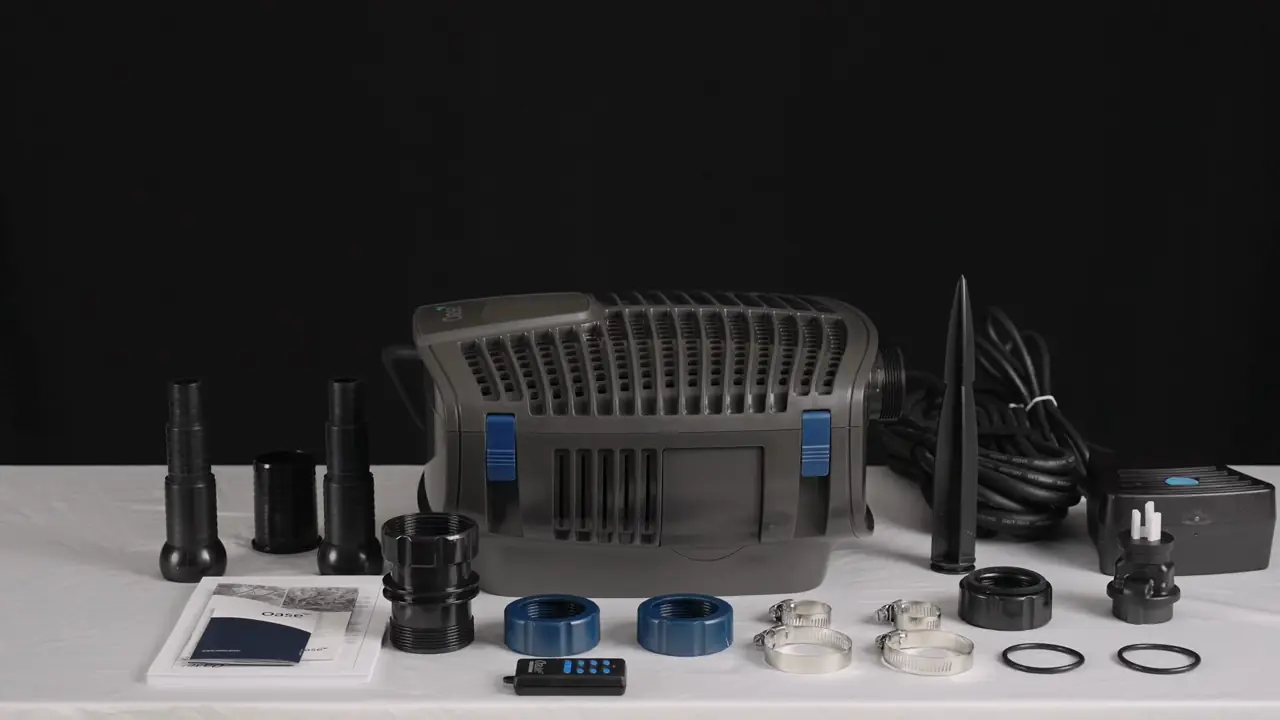 OASE AquaMax Eco Twin filterpumpe med slangetuter, fjernkontroll og deler lagt fram på et bord