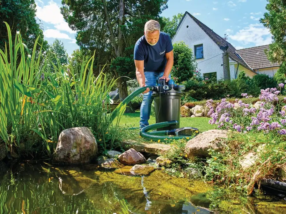 Trykkfilter til hagedam: OASE FiltoClear 31000 står ved dammen mens slangen kobles til
