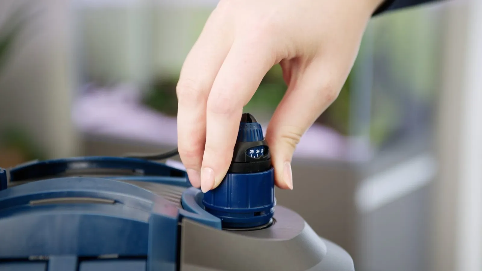 Hånd på HeatUp-varmeren i lokket på OASE FiltoSmart Thermo ytterfilter