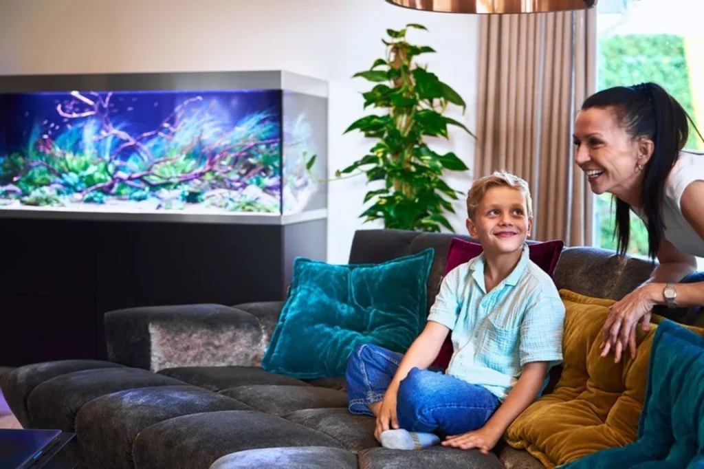 Mor og sønn i sofaen ser på akvariet i OASE HighLine 600 sort