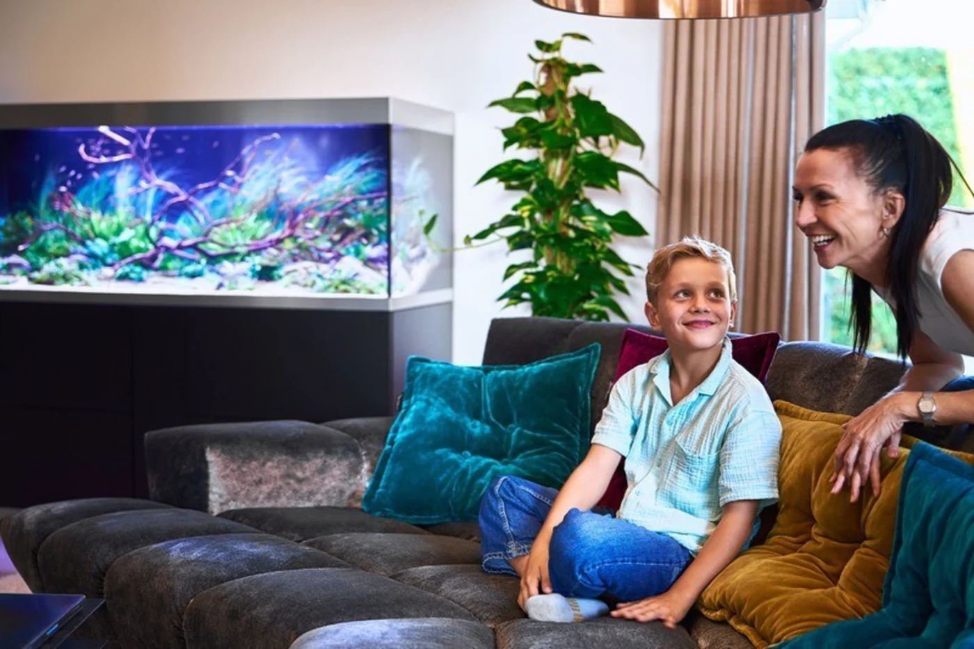 Mor og sønn i sofaen ser på akvariet i OASE HighLine 600 sort