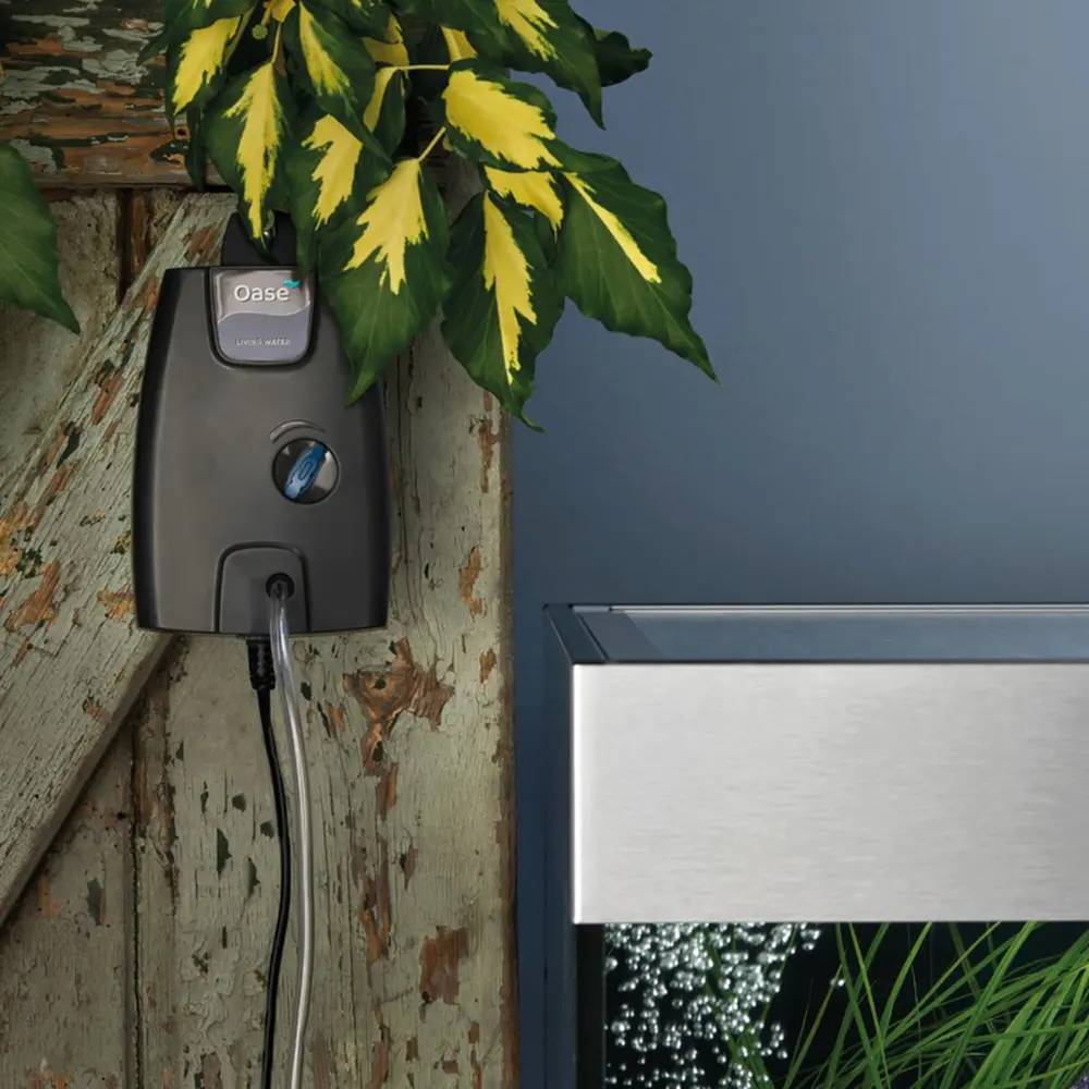 OASE OxyMax 100 luftpumpe med ett uttak henger på veggen ved siden av akvariet