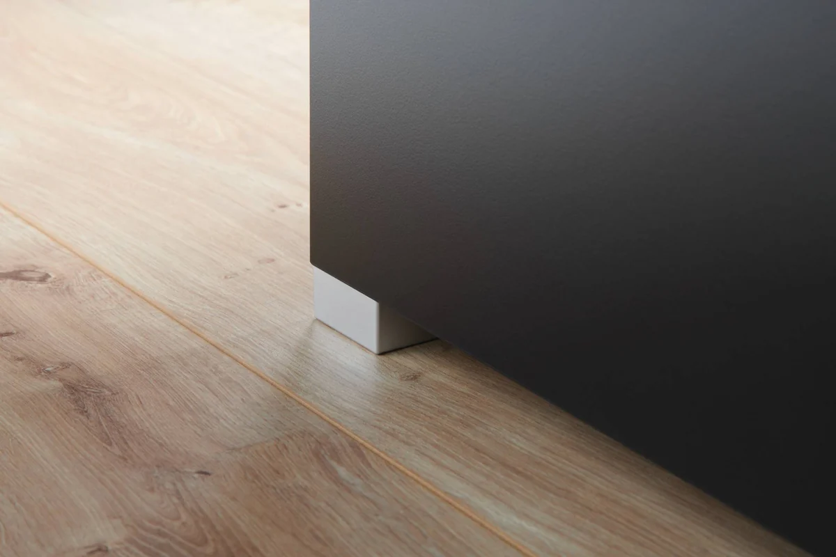 Fot i aluminiumslook under sort OASE StyleLine-skap på tregulv
