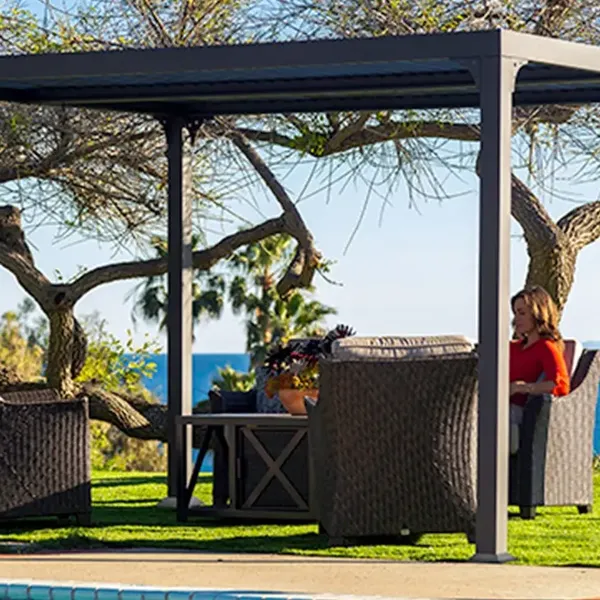 Pergola i grå aluminium med loungemøbler på plenen ved havet