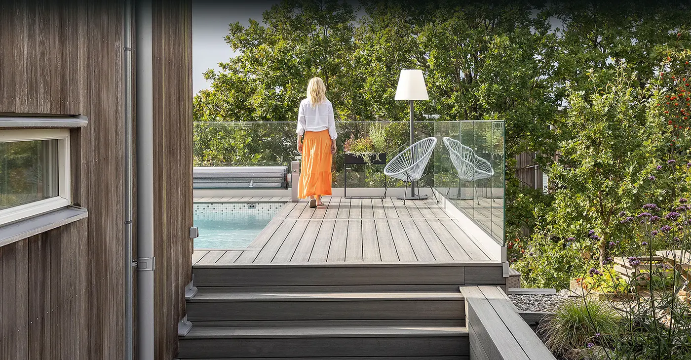 Kvinne i oransje skjørt på lys grå terrasse i Woodlon Elegance trekompositt med trapp og hage