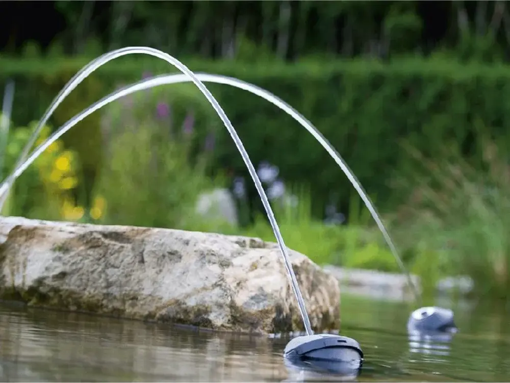 To Water Jet Lightning sender vannbuer over en stein i hagedammen